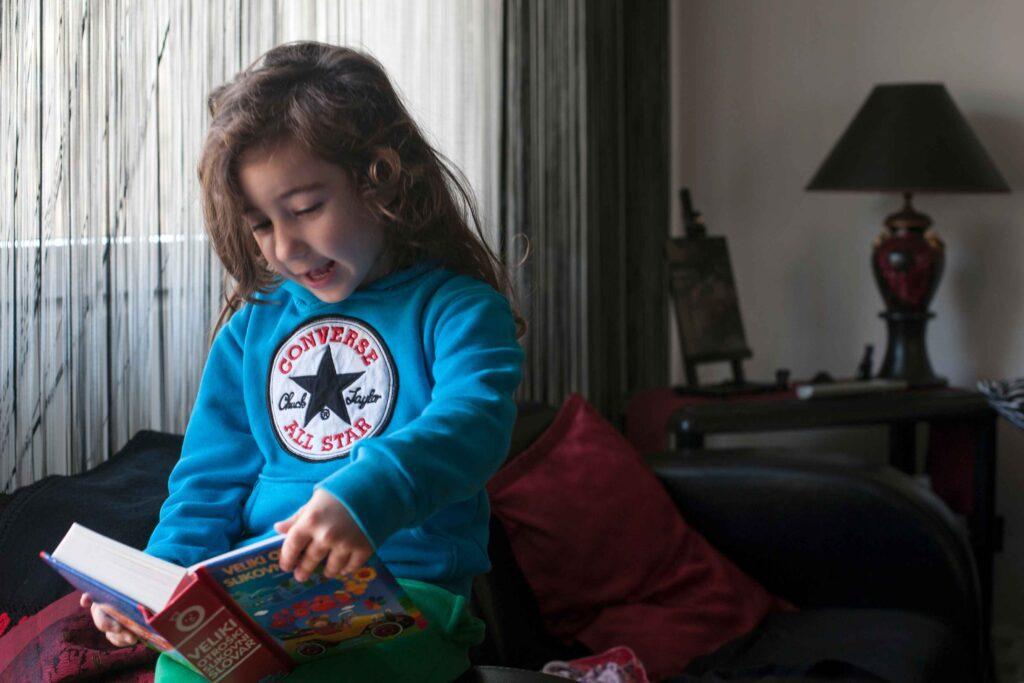 girl reading book while siting sofa home girl reading book while siting sofa home