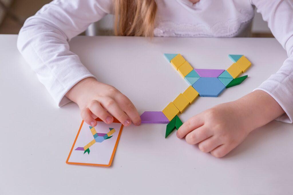 girl student sits desk classroom collects figures puzzles small toys Shapes Strengthen Spatial Awareness